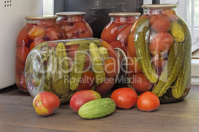 Canned tomatoes and cucumbers in large glass jars.