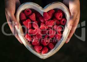 Young Woman Hands Holding Heart Shaped Bowl of Raspberries