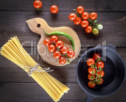 long yellow raw spaghetti and red cherry tomatoes