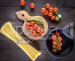 long yellow raw spaghetti and red cherry tomatoes