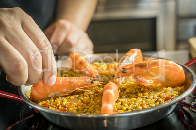 Chef is adding seafood to paella, close up