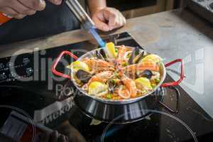 Chef is frying seafood of paella with burner