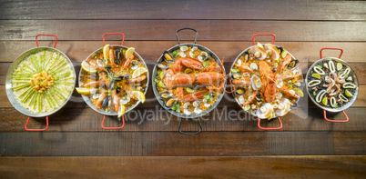 Assorted paella on wooden table, above view