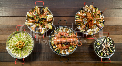 Assorted paella on wooden table, above view
