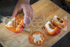 Chef cutting red bell pepper on wooden broad