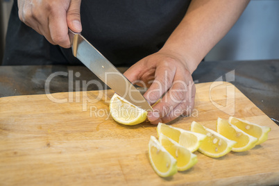 Chef slicing Lemon on wooden cutting board