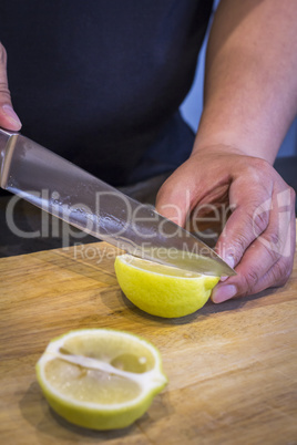 Chef slicing Lemon on wooden cutting board