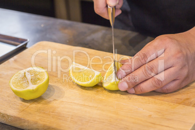 Chef slicing Lemon on wooden cutting board