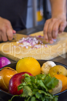 Fresh fruit in the kitchen with chef cutting onion to prepare fo