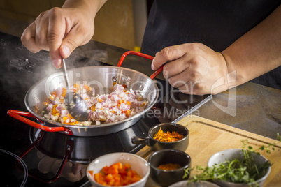 Chef is frying food ingredient for cooking paella