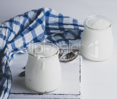 glass jars with homemade yogurt on a white wooden board