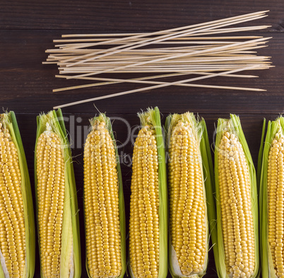 fresh ripe corn cobs on a brown wooden board