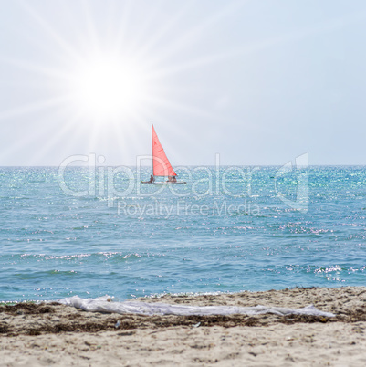 boat with red sails swims away by the sea