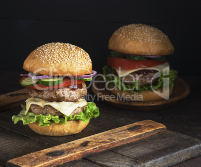 large burger with two fried cutlets, cheese and vegetables