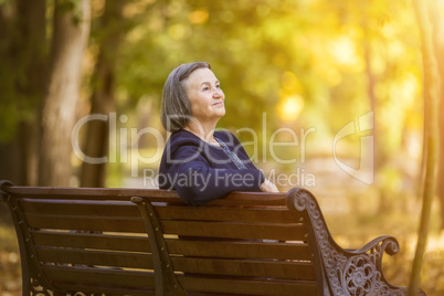 Elderly woman sitting on a bench in autumn park