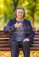 Puzzled aging woman having heart attack outdoors