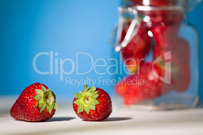 Close up of two strawberries on a table with blue background