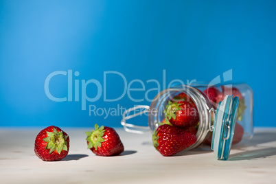 Strawberries and a glass jar full of strawberries lying down on