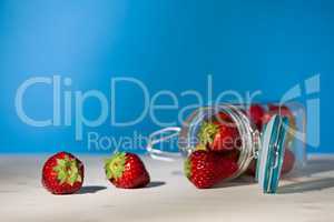 Strawberries and a glass jar full of strawberries lying down on