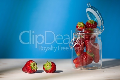 Strawberries on a table and a glass jar full of strawberries