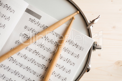 Music score drumsticks and drum tuner over a snare drum