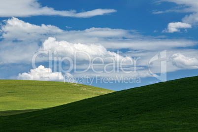 White clouds above green hills