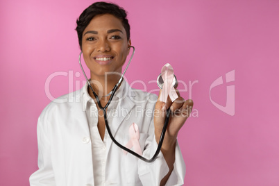 Smiling nurse holding pink ribbon breast cancer awareness