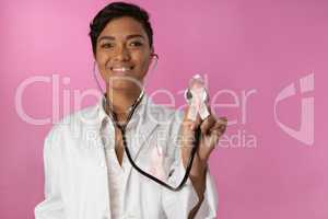 Smiling nurse holding pink ribbon breast cancer awareness