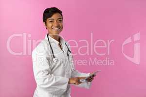 Smiling nurse wearing breast cancer awareness using tablet