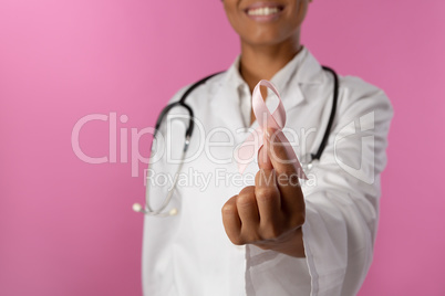 Smiling nurse holding a pink ribbon for breast cancer awareness