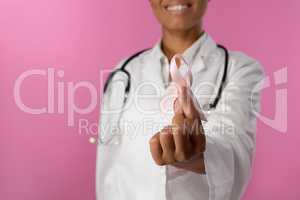 Smiling nurse holding a pink ribbon for breast cancer awareness