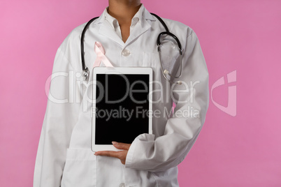 Nurse wearing pink ribbon holding a tablet in her hand