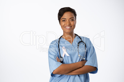 Smiling professional nurse with crossed arms wearing pink ribbon