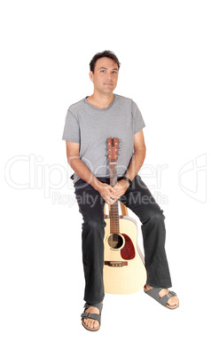 Man sitting with his guitar between his legs