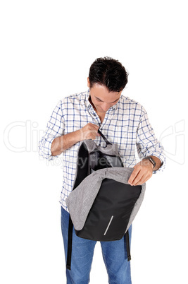 A young tall man looking into his backpack