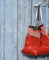 red leather boxing gloves hanging on an old blue wooden wall