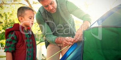 Father and son setting up the tent at campsite