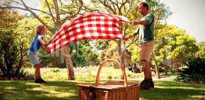 Father and son spreading the picnic blanket