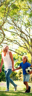 Mother and son walking in the park with football