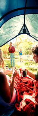 Couple having coffee and looking at kids playing outside the tent