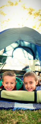 Smiling siblings lying outside the tent