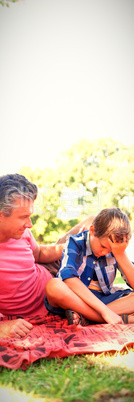 Father consoling his son at picnic in park