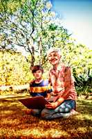 Grandmother and grandson using laptop in the park