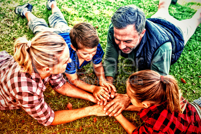 Family lying and putting their hands together in park