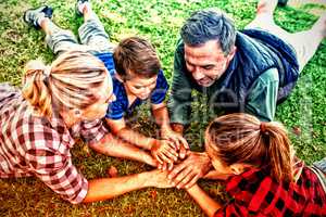 Family lying and putting their hands together in park