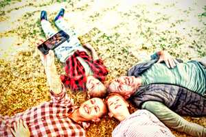 Happy family lying on the grass and taking selfie