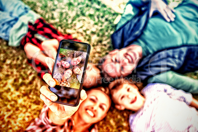 Happy family lying on the grass and taking selfie