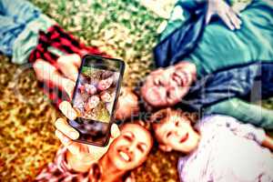 Happy family lying on the grass and taking selfie