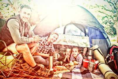 Smiling family having snacks outside the tent on a sunny day