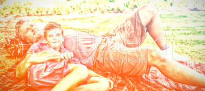 Father and son lying on picnic blanket in park
